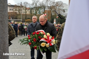 Mężczyzna kładzie kwiaty przy pomniku