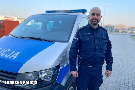 Policjant na tle radiowozu