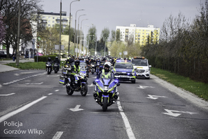 Policyjny motocykl prowadzi paradę motocyklową.