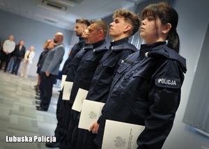 Policjanci trzymający w dłoniach akty ślubowania.