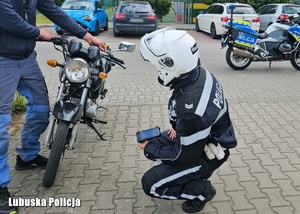 Policjant podczas sprawdzania stanu technicznego motocykla.