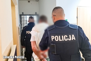 Policjanci prowadzą zatrzymanego mężczyznę.