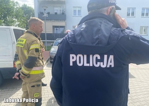 Policjant stojący obok strażaka.