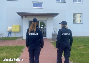 Policjanci idący w kierunku bloku mieszkalnego.