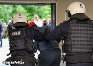 Policjanci przeprowadzają zatrzymanego mężczyznę podczas ćwiczeń.