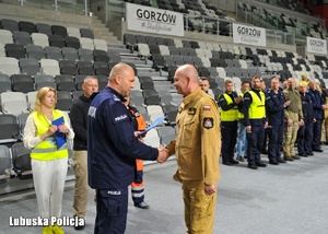 Policjant wręcza podziękowania strażakowi.