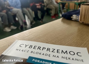Książka na stoliku w tle widoczne osoby biorące udział w spotkaniu