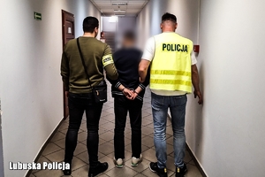 Policjanci prowadzą zatrzymaną osobę.