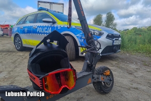 Hulajnoga elektryczna na tle radiowozu.