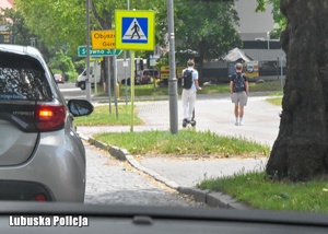 Chłopiec jadący hulajnogą na chodniku.