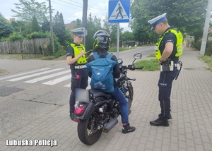 Policjanci ruchu drogowego podczas kontroli drogowej motocyklisty.