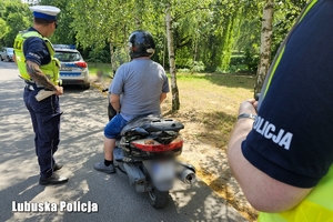 Policjant drogówki podczas kontroli drogowej motocyklisty.