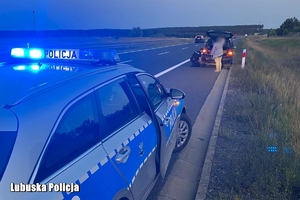 policjant zmienia koło w samochodzie