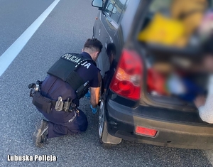 policjant zmienia koło w samochodzie