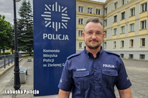 policjant stoi przed banerem