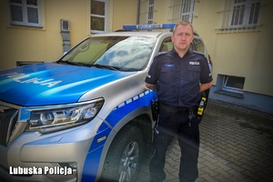 policjant stoi przy radiowozie
