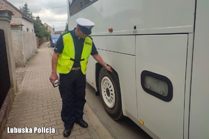Policjant kontroluje stan techniczny autokaru