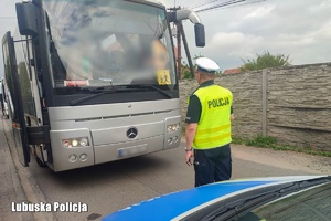 Policjant kontroluje stan techniczny autokaru
