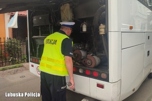 Policjant kontroluje stan techniczny autokaru