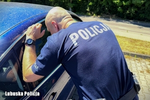 policjant spogląda przez okno samochodu