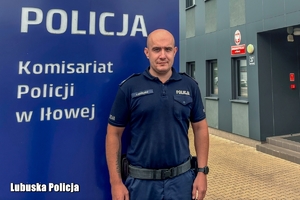 policjant stoi przed banerem