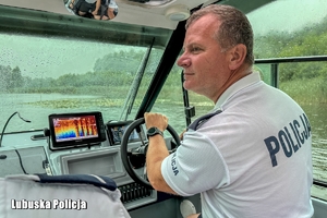 policjant na łodzi obserwuje jezioro