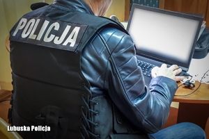 Policjant pisze na komputerze.