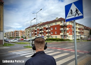 Mężczyzna w słuchawkach stojący przy przejściu dla pieszych.
