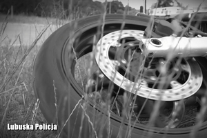 Obrazek przedstawiający koło motocykla na trawie.