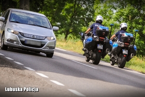 Policyjni motocykliści na drodze.