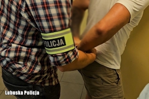 policjant zakłada kajdanki podejrzanemu