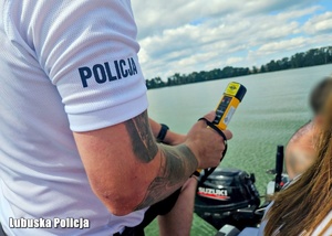 Policjant podczas sprawdzania stanu trzeźwości osoby na łódce.