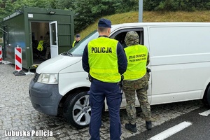 Policjant i strażnik graniczny kontrolują pojazd.