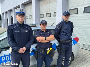 Policjanci stojący przy radiowozie.