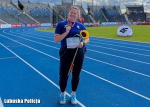 Kobieta w stroju sportowym pozuje do zdjęcia z medalem.