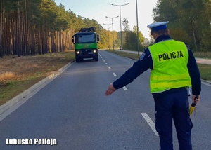 Policjant zatrzymuje ciężarówkę do kontroli drogowej.
