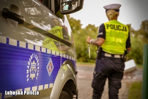 Policjantka stojąca przy radiowozie.