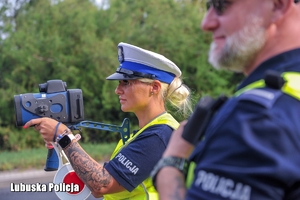 Policjantka sprawdza prędkość jadących pojazdów.