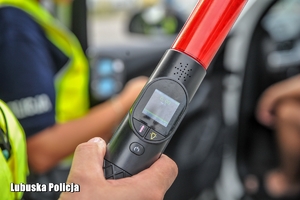policjant trzyma urządzenie do badania trzeźwości