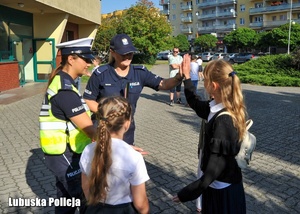 Policjantka przybija piątkę z dzieckiem podczas akcji Bezpieczna Droga do Szkoły.