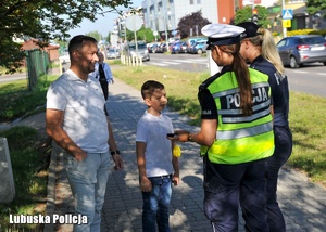 Policjantka z policjantem rozmawia z chłopcem.
