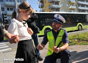 Policjant rozmawia z dziewczynką podczas akcji profilaktycznej.