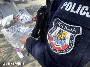 Policjant rozdaje ulotki profilaktyczne.