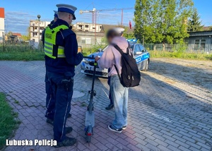 Policjant podczas kontroli drogowej osoby na hulajnodze elektrycznej.