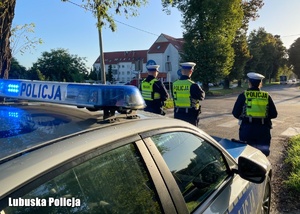 Policjanci drogówki stojący przy radiowozie.