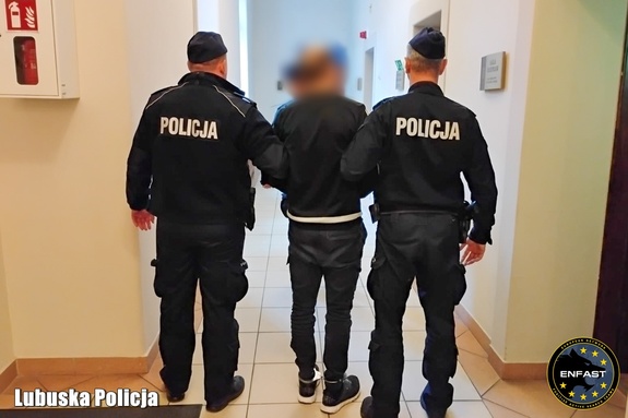 Zatrzymany mężczyzna doprowadzany przez policjantów.