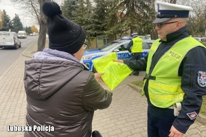 policjant przekazuje kamizelkę rowerzystce