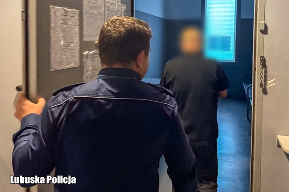 policjant odprowadza mężczyznę do celi