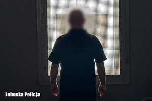 mężczyzna przy oknie z kratą