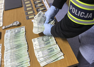 policjant przegląda gotówkę i złoto